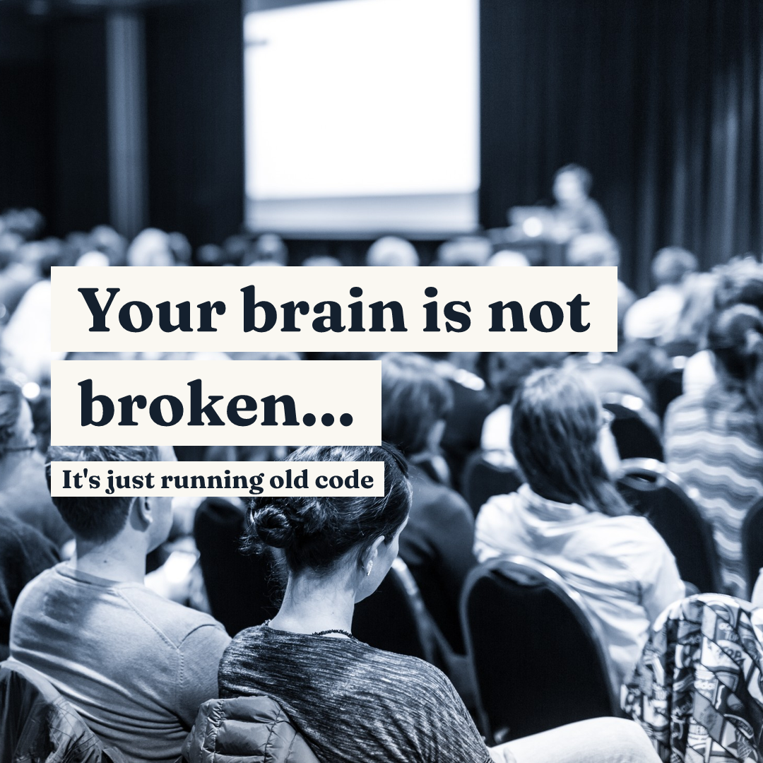 Text 'Your brain is not broken... It's just running old code' over a blurred audience watching a presentation.